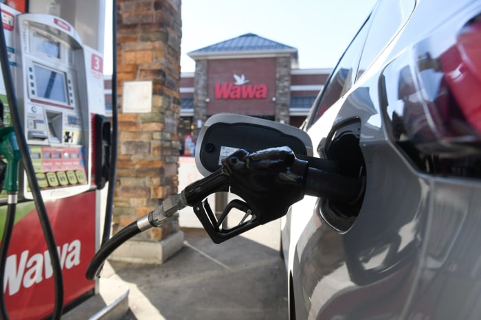 A close-up of a fuel nozzle in a car's gas tank at a Wawa gas station.