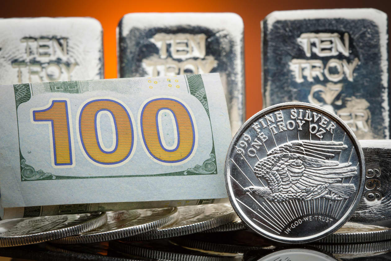 A $100 bill, silver bars, and silver coins.