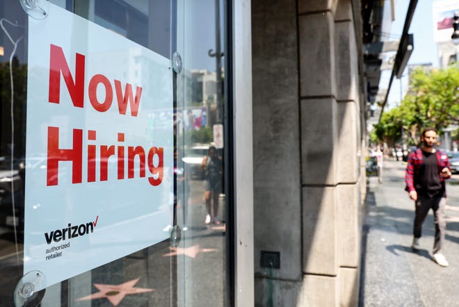A "Now Hiring" sign is posted at a Verizon store in Los Angeles on July 26, 2022.